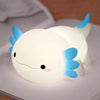 Veilleuse axolotl en silicone allumée à nageoires bleues posée sur un livre - Bébé Lova