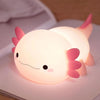 Veilleuse axolotl en silicone allumée à nageoires roses posée sur un livre - Bébé Lova