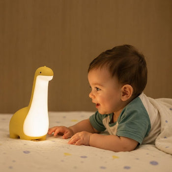 Bébé allongé sur un lit observant la veilleuse dinosaure jaune allumée - Bébé Lova