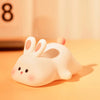 Veilleuse lapin RabbitLight couchée sur table de chevet ambiance chaleureuse orangée - Bébé Lova