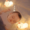 Bébé dormant paisiblement à côté d’une veilleuse chat lumineuse apaisante - Bébé Lova